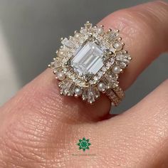 a close up of a person's hand wearing a ring with an emerald and white diamond