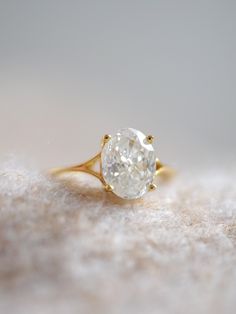 a close up of a ring with a white diamond on the top and gold band