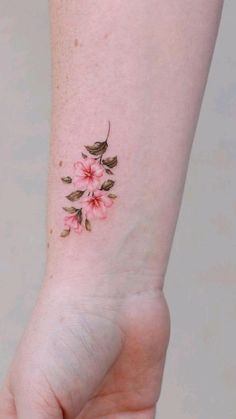 a small pink flower tattoo on the wrist