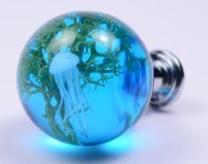 a blue glass ball with a jellyfish in the water on it's side