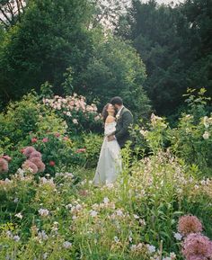 a bride and groom kissing in a field of flowers