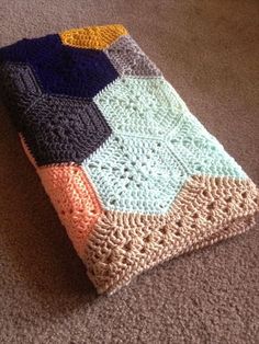 a crocheted blanket is laying on the floor with it's edges folded