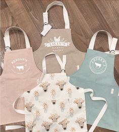 three aprons with different designs on them sitting on a wooden floor next to each other