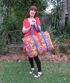 a woman is holding a colorful bag in her hands while standing on the grass outside