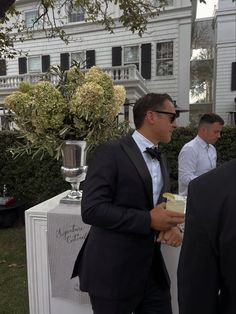 a man in a tuxedo standing next to another man