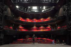 a man standing in front of an auditorium filled with red seats