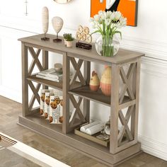 a vase with flowers on top of a wooden shelf next to pictures and other items