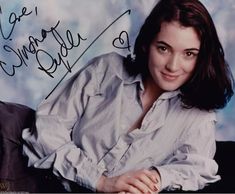 an autographed photo of a woman sitting on a chair with her hand on her chest