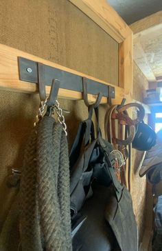 a horse's saddle hanging on a wooden wall with hooks and other items attached to it