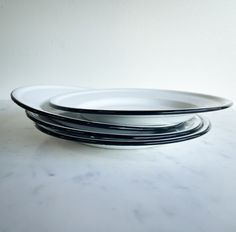 three black and white plates sitting on top of a marble countertop next to each other