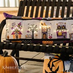 a bench that has some decorations on it and lights in the windows behind it, along with two pumpkins