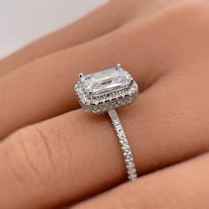 a woman's hand holding an engagement ring with a diamond in the center and side stones on it