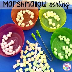 marshmallows sitting in bowls and spoons on a blue table with the words marshmallow sorting