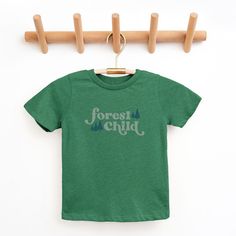 Looking for a cute tee for your kids? We have the perfect Forest Child graphic tee addition to their closet! Also available in toddler tees. Cute Green Tops With Name Print, Green Cotton T-shirt With Name Print, Cute Green T-shirt With Letter Print, Green Family Matching Graphic Print Shirt, Green Family Matching Shirt With Graphic Print, Green Graphic Print Family Matching Shirt, Green Short Sleeve T-shirt For Family Matching, Green Family Matching T-shirt With Graphic Print, Family Matching Green T-shirt With Graphic Print