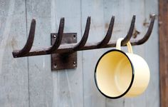 a cup hanging from a hook on a wooden wall with metal bars attached to it