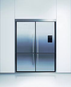 two stainless steel refrigerators are in the middle of an empty room with white walls