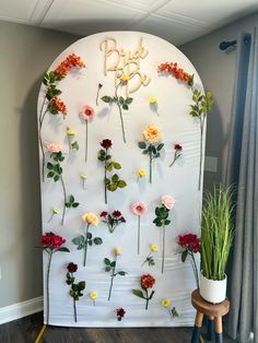 flowers are arranged on a white wall with the word baby spelled in cursive letters