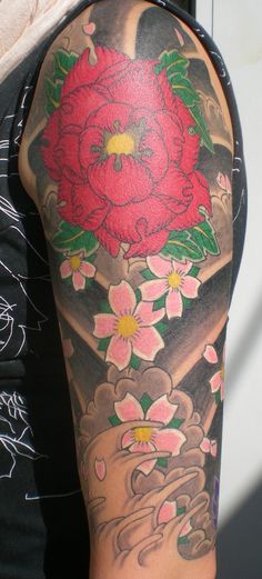 a man with a tattoo on his arm holding a red flower in front of him