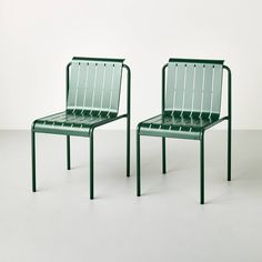 two green chairs sitting next to each other on top of a white floor covered ground