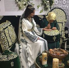 two women dressed in traditional clothing sitting on a couch next to each other and writing