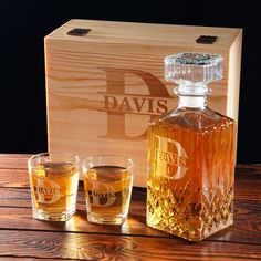 two glasses and a bottle of whiskey sitting next to a wooden box