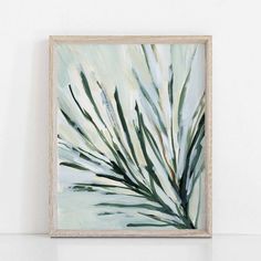 an abstract painting with green and white leaves in a wooden frame on a shelf next to a wall