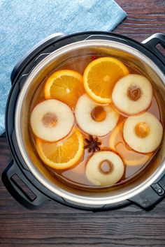 sliced oranges and anise in a pot of water on top of a wooden table