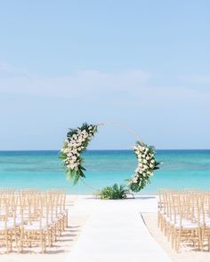 an outdoor ceremony setup with white flowers and greenery on the aisle leading to the ocean