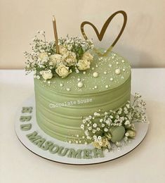 a green cake with flowers and candles on top