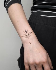 a woman's arm with a small flower tattoo on the left wrist and right hand