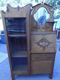 an old fashioned wooden cabinet with mirror on the top and bottom shelf, in front of a brick sidewalk