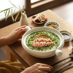 a person sitting at a table with some food in a bowl on top of it