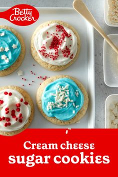 four cookies decorated with cream cheese and sprinkles are on a white tray