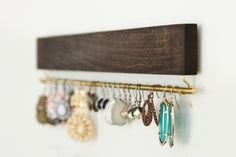 a wooden rack with earrings hanging from it's sides and an earring holder attached to the wall