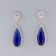 "Would you love to sparkle even brighter on your special day? Looking for your something Blue? Gorgeous bridal earrings have been created using a long sapphire blue crystal in a cz halo and are completed by your choice of earpost. Perfect for the Mother of the bride. Style #1~ Art Deco-inspired earpost. CZ crystals studded in a double swirl. Style #2~ Teardrop Earpost -pearl CZ crystal in a halo of smaller crystals. Post back Style #3~ Smaller Teardrop earpost, inverted pear crystal with a halo Blue Sapphire Pear-shaped Earrings, Blue Pear-shaped Party Earrings, Blue Drop Bridal Earrings For Formal Events, Blue Drop Bridal Earrings For Formal Occasions, Blue Drop Bridal Earrings, Blue Crystal Dangle Bridal Earrings, Blue Pear-shaped Teardrop Earrings For Anniversary, Blue Cubic Zirconia Teardrop Earrings For Wedding, Blue Cubic Zirconia Teardrop Earrings