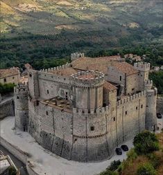 an aerial view of a castle surrounded by mountains