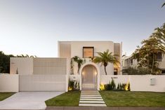 a white house with palm trees in the front yard and stairs leading up to it