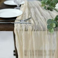 the table is set with plates, silverware and white flowers on top of it