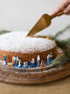 someone is cutting into a cake with frosting on it and figurines in the foreground