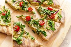 a wooden cutting board topped with slices of pizza covered in veggie toppings