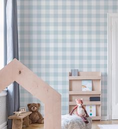 a child's bedroom with blue and white checkered wallpaper, teddy bear in the corner