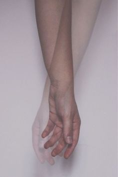 two hands reaching for each other in front of a white wall with no one on it