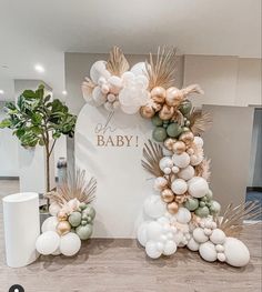 a baby shower with balloons and greenery on the floor next to a sign that says it's a baby