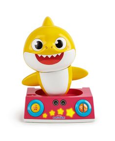 a yellow and white toy shark on top of a pink radio box with its mouth open