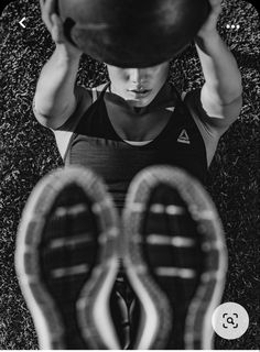 black and white photograph of a man holding a ball above his head in the grass