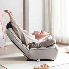 a woman laying on top of a chair in a living room