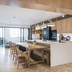 an open kitchen and dining area with wooden flooring, white countertops and cabinets