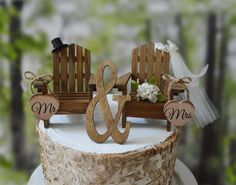 a wedding cake with two wooden chairs and mr and mrs signs on top, sitting next to each other