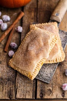 two pastries sitting on top of a wooden table next to an orange and cinnamon stick