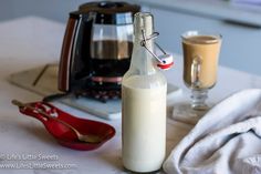 a bottle of milk sitting on top of a table next to a cup and saucer